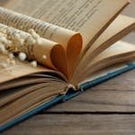 Close-up of an open vintage book with heart-shaped pages and dried flowers, conveying a romantic and nostalgic feeling.